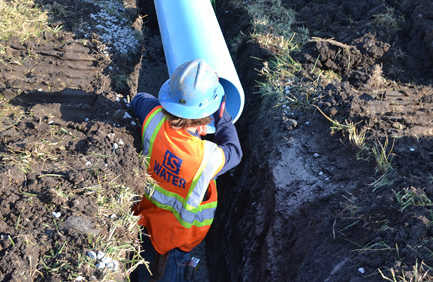 water utilities employee laying underground pipe
